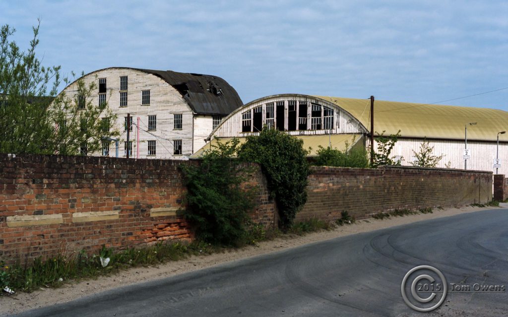 Brick wall, old timber sheds at factory site