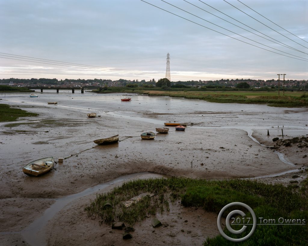 Tidal mud, boats, razor wire and overhead power lines
