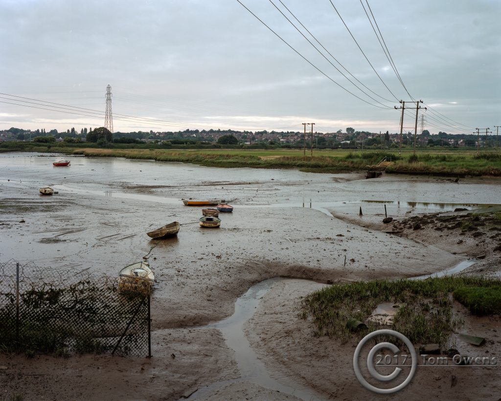 Tidal mud, boats, razor wire and power lines